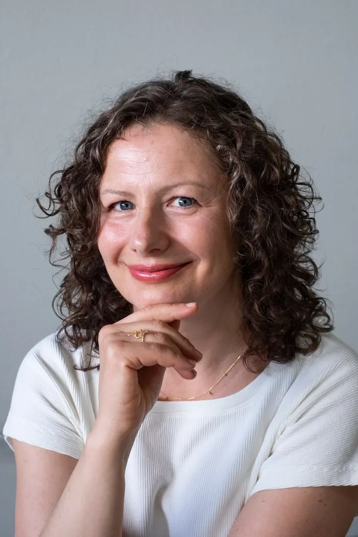 Porträt von Veronika Mayr, lächelnd, das Kinn auf die Hand gestützt